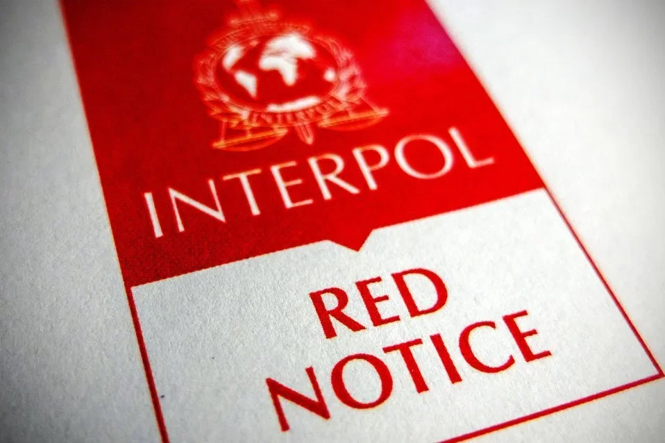 Zbliżenie na czerwono-biały dokument Interpolu z napisem „RED NOTICE”.